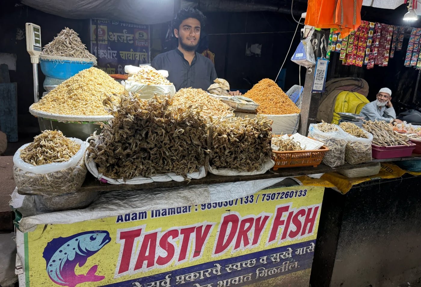 The shop at Hadapsar Mandai in the evening, lit up over heaps of dry fish